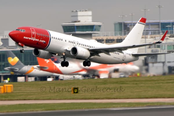 Side view of a twin engined jet airliner flying from right to left at a very low altitude