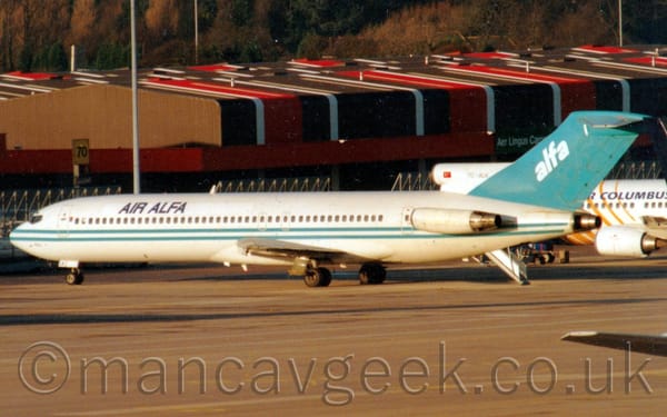 Side view of a 3 engined jet airliner with the engines mounted on the rear fuselage, parked facing to the left and slightly away from the camera.