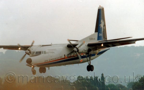 Side view of a white, high-winged, twin propellor-engined airliner flying from right to left