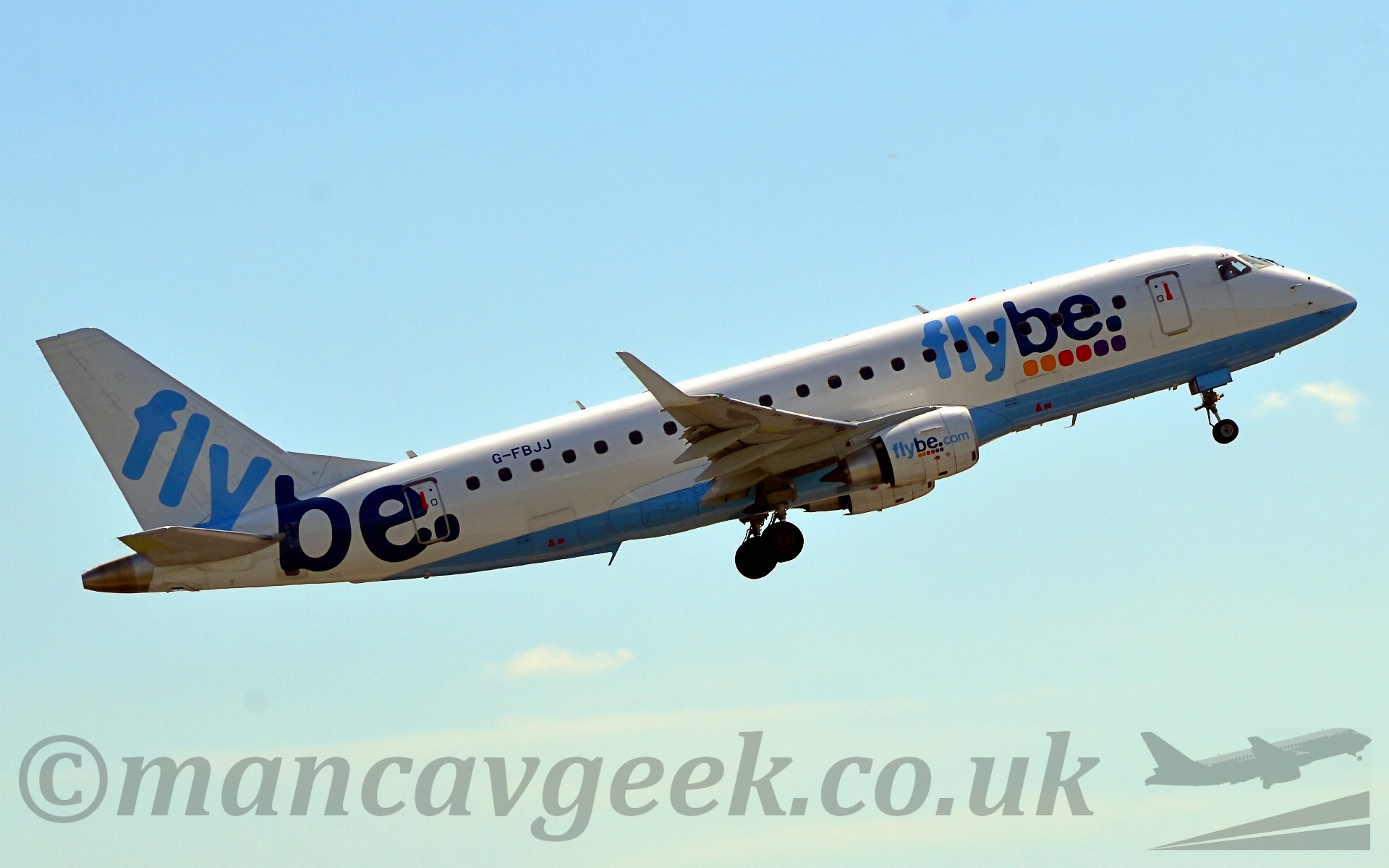 Side view of a twin engined jet airliner flying from left to right with it's undercarriage lowered and flaps deployed from behind the wing, and it's nose raised fairly steeply. The plane has a sky blue belly, the rest being white. There are large "Flybe" titles in light and dark blue on the forward fuselage above some multi-coloured dots, and larger similar titles on the tail and rear fuselage. Behind, the sky is fiding from a clear blue at the top to a hazy white at the bottom.