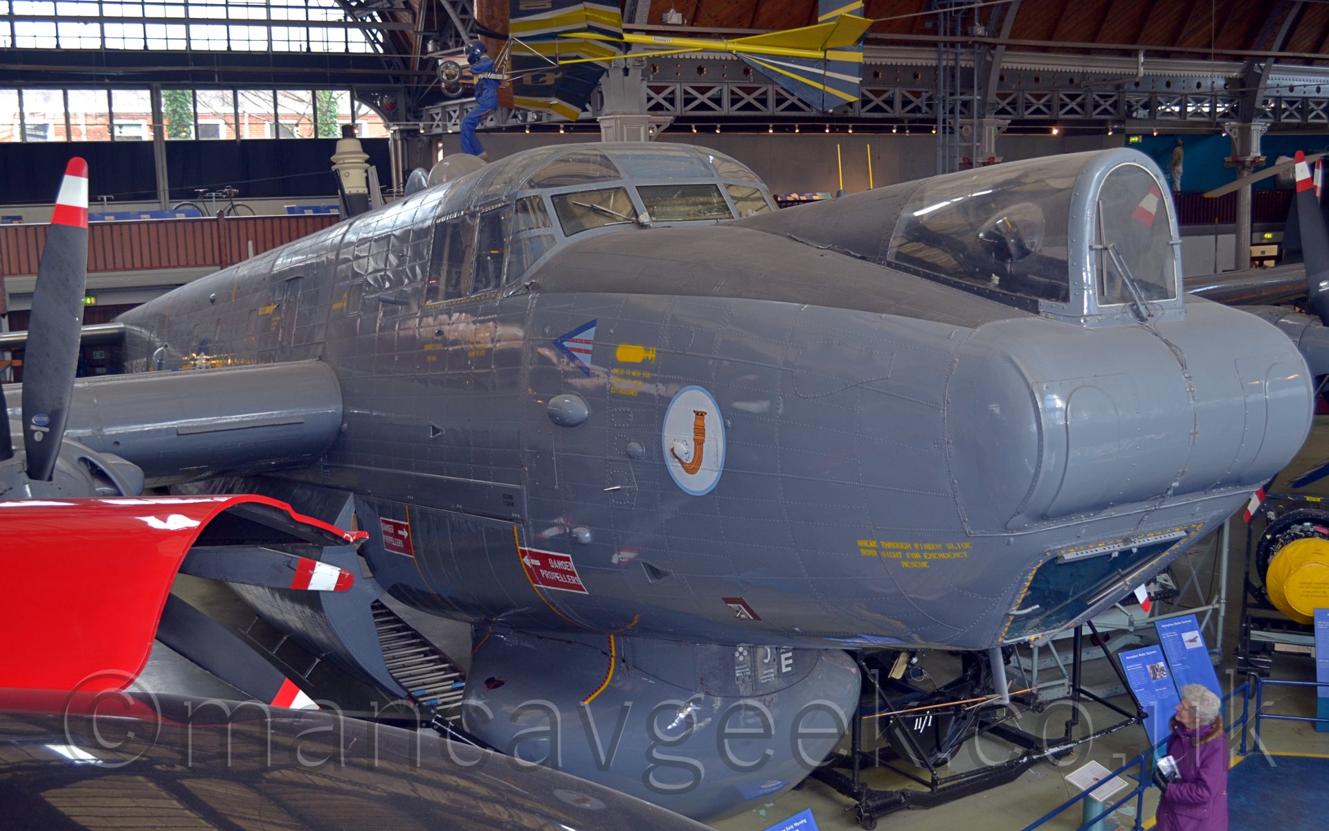 Close up of the nose and forward fuselage of a 4 engined grey military aircraft on display in a museum.