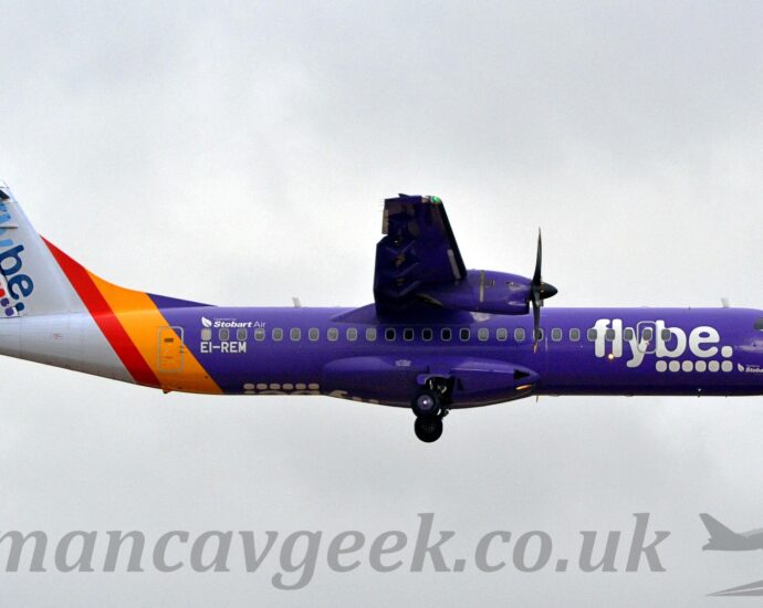 Side view of a high-winged, twin propellor-engined purple airliner flying from left to right at a very low altitude, with undercarriage extended and flaps deployed from the rear of the wings, suggesting it is about to land. The plane is mostly a lush purple, with a yellow and red band around the rear fuselage, and a whitetail and tail-cone. There are large white "FlyBe" titles over 6 white dots on the forward fuselage, a design replicated diagonally on the tail, only this time the text is in 2 shades of blue, and with 2 yellow dots, 2 red dots, and 2 purple. There are white "Stobart Air" titles under the forward fuselage, just over the nose-wheel doors, repeated over the rear passenger cabin windows, and the registration "EI-REM" just under those windows, also in white.