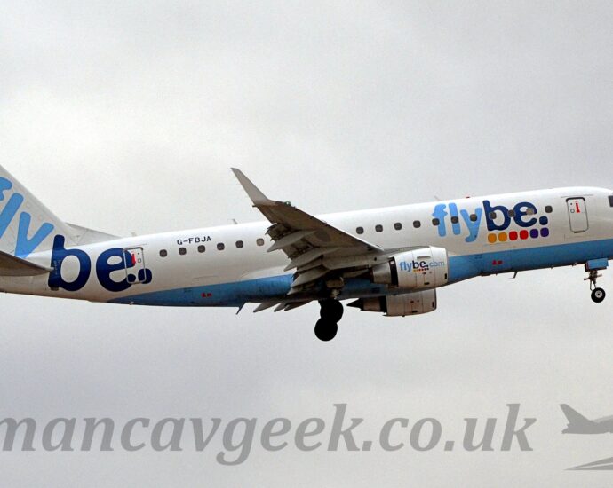Side view of a twin engined jet airliner flying from left to right at a very low altitude, with undercarriage lowered and flaps deployed from the rear of the wings, suggesting it is about to land. The plane is mostly white, with a pale blue belly, and two-tone light and dark blue "FlyBe" titles on the side of the forward fuselage, over pairs of yellow, red, and purple dots. The same logo appears in a smaller form on the sides of the white engine pods under the wings. A larger version of the logo, without the dots, appears diagonally on the white tail and rear fuselage, just aft of the black registration "G-FBJA". Flat grey sky fills the rest of the frame.