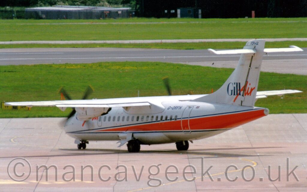 Rear side view of a high-winged, twin propellor-engined airliner taxiing from right to left and away from the camera. The plane is white, with a red wedge, outlined in blue, starting just behind the cockpit and running rearwards, getting wider as it moves to the rear. The blue registration "G-ORFH" is on the upper rear fuselage, just forward of the rear door, with a small British flag just aft of the door. The tail is white with blue "Gill" and red "Air" titles, the latter part seemingly hand-written. Grey concrete apron fills the foreground, with green grass in the background leading up to a grey runway and more grass, with a large black hangar right at the top of the frame.