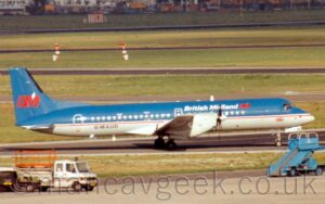 Side view of a twin propellor-engined airliner taxiing from left to right along a black taxiway. The plane is blue on top and light grey on the lower half, with a thin white and red stripe running along the body, just below the passenger cabin windows. There are white "British Midland" titles on the upper forward fuselage, just aft of a red "BM" logo, with a white diamond in the angle of the "M", and a small, Red, white, and blue UK flag on the lower forward fuselage below the cockpit windows. The black registration "G-MAUD" is on the lower rear fuselage. A larger version of the red "BM" logo fills the bottom of the blue tail. Grey concrete apron fills the foreground, with a blue set of mobile airstairs parked on the right, and a couple of white trucks on the left, and s strip of green grass separating this apron from the taxiway. More strips of grass in the background separate a further 3 taxiways stretching across the frame, as well a black runway in the distance, with more grass right at the back.