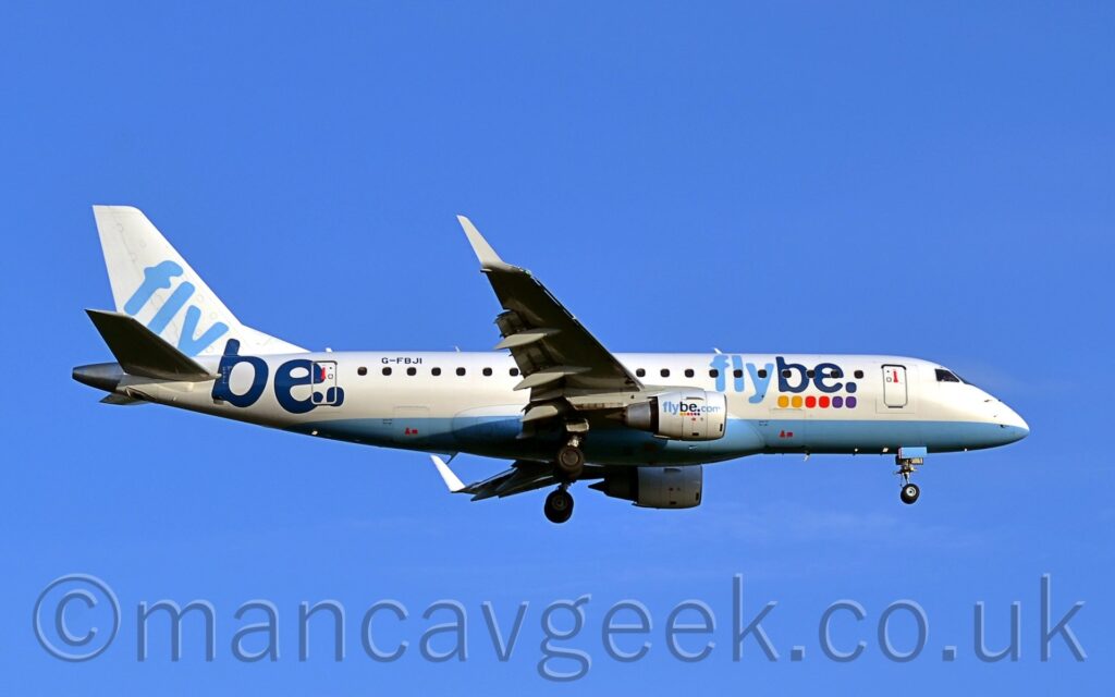 Side view of a twin engined jet airliner flying from left to right at a low altitude, with undercarriage lowered, and flaps extended from the front and rear of the wings, suggesting it is about to land. The plane is mostly white, with a pale blue belly. There are light and dark blue, billboard-style, "FlyBe" titles on the forward fuselage, over a series of 2 yellow, 2 red, and 2 purple dots, a logo repeated on the sides of the white engine pods under the wings. Larger, diagonal "FlyBe" titles fill the white tail and rear fuselage. The black registration "G-FBJI" is on the upper rear fuselage. Blue sky fills the rest of the frame.